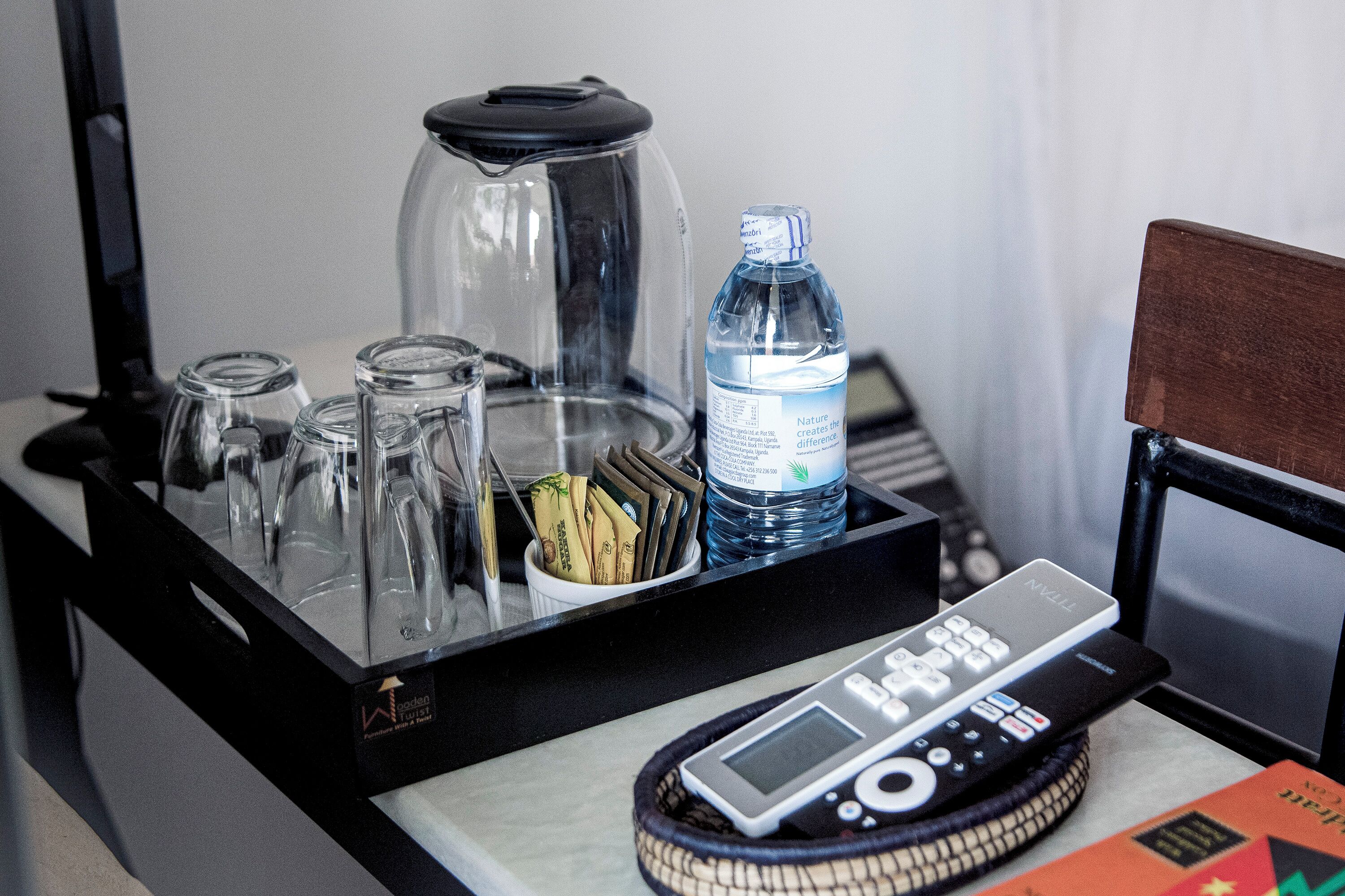 A tray with a water bottle, a glass carafe, and a remote control on a table.