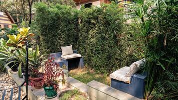 Un jardin agrémenté d’un espace détente, de plantes en pot et d’un mur en briques.
