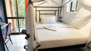 A single bed with a canopy, a small window, and a chair.