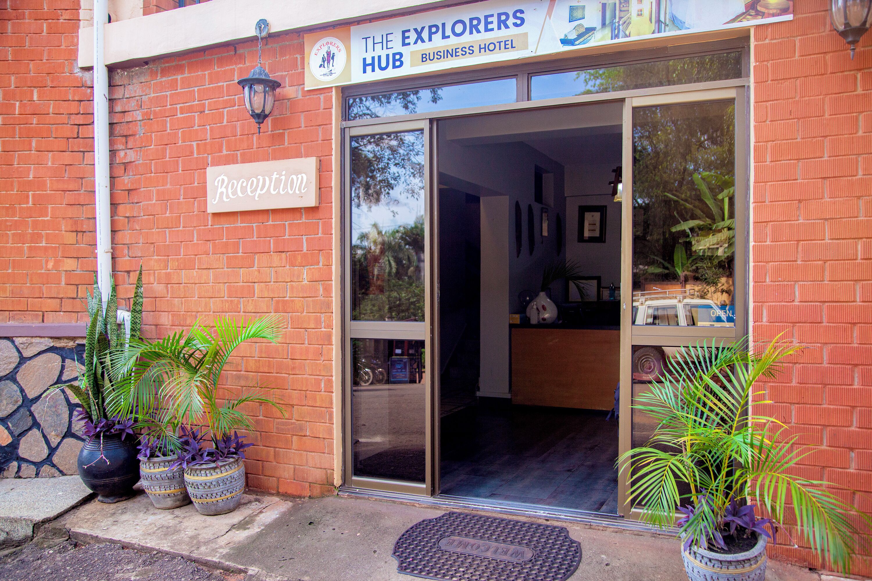 Un edificio de ladrillo con un letrero que dice 'Recepción' y 'The Explorers Hub Business Hotel'.
