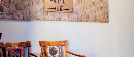 Een houten stoel met een gekleurd kussen en een muur met een reliëf stenen patroon.