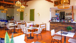 Ein Restaurant mit Holzbalken, Korbschwinglampen und einer Bar mit verschiedenen Flaschen.