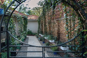A garden with a brick wall, a tiled roof, and various plants. - The Explorers Hub (Kampala)