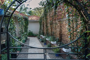 Un jardín con muro de ladrillo, techo de tejas y diversas plantas.