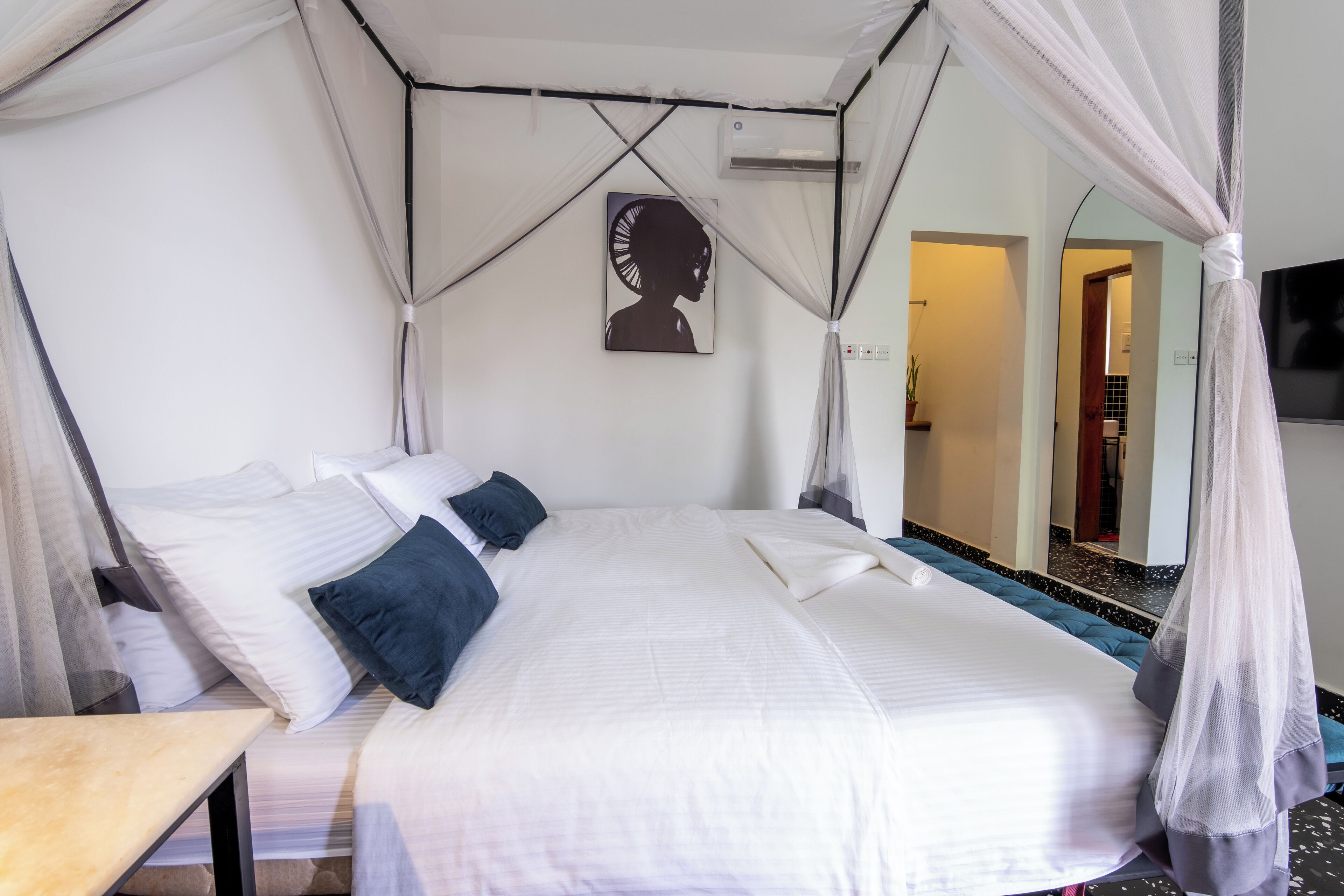 A bed with white bedding, a bedside table, and a canopy.