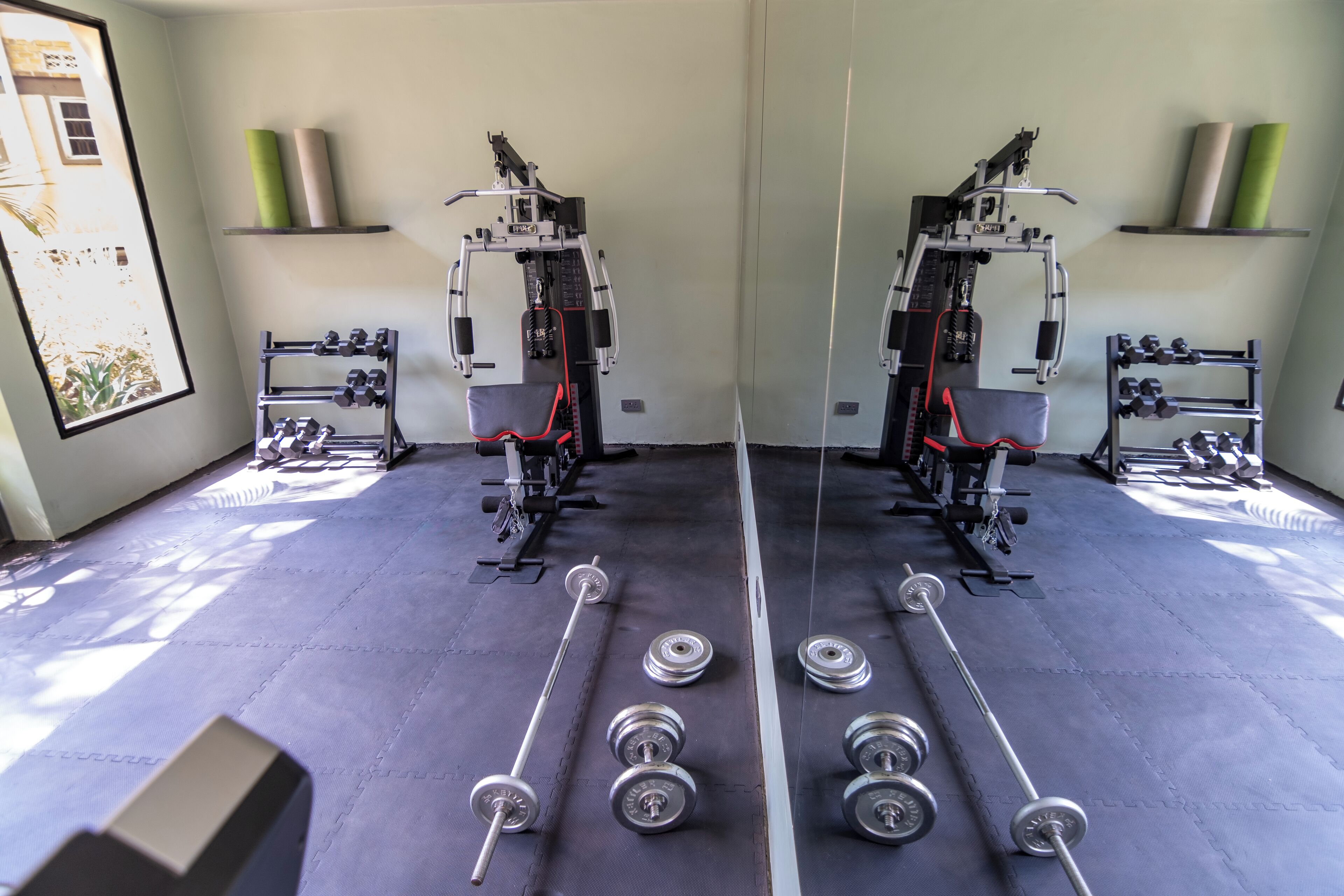 A gym with mirrored walls, weight racks, and exercise equipment.