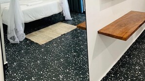 Ein modernes Hotelzimmer mit einem Bett, einem Fernseher, einer Holzablage und einem Spiegel.
