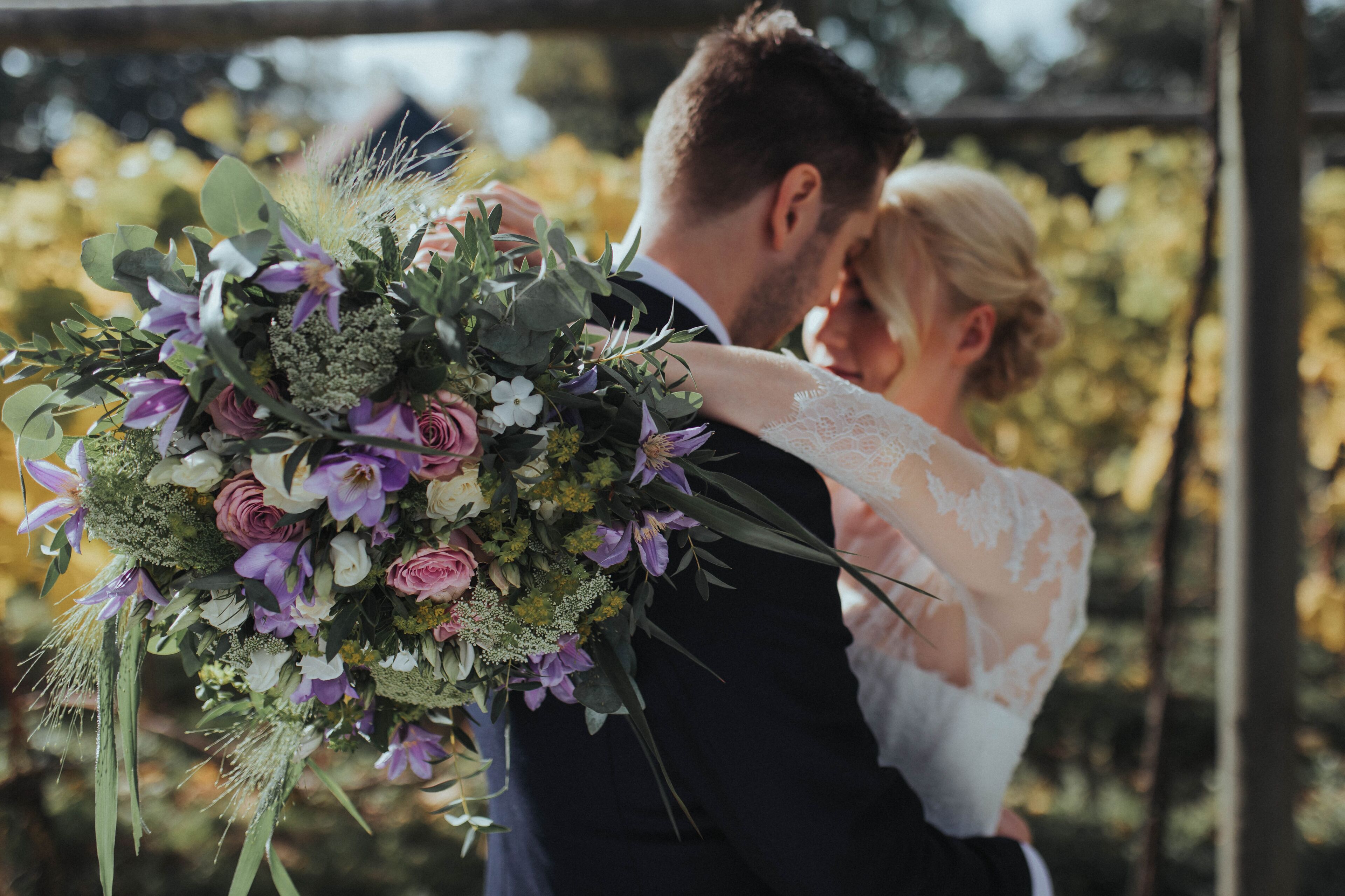 Una pareja abrazándose con un ramo de flores.