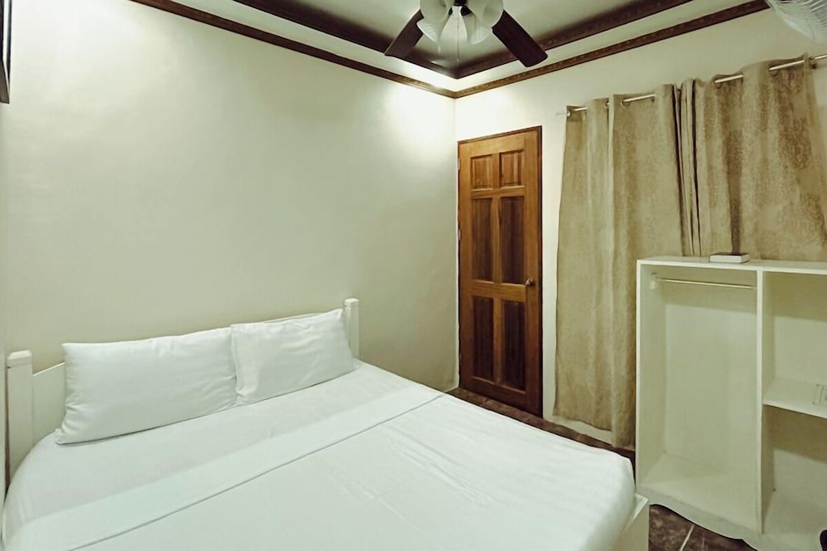 A bedroom with a bed, a wardrobe, a door, and a ceiling fan.