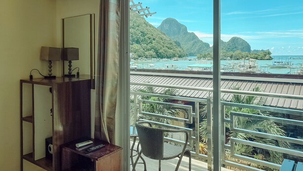 Ein Zimmer mit großem Fenster und Blick auf eine Küstenlandschaft mit Booten und Bergen.