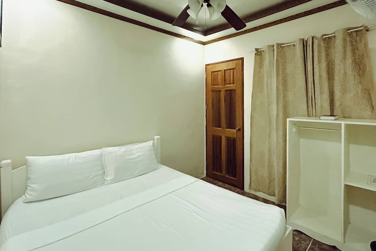 A bedroom with a bed, a wooden door, and a white wardrobe.