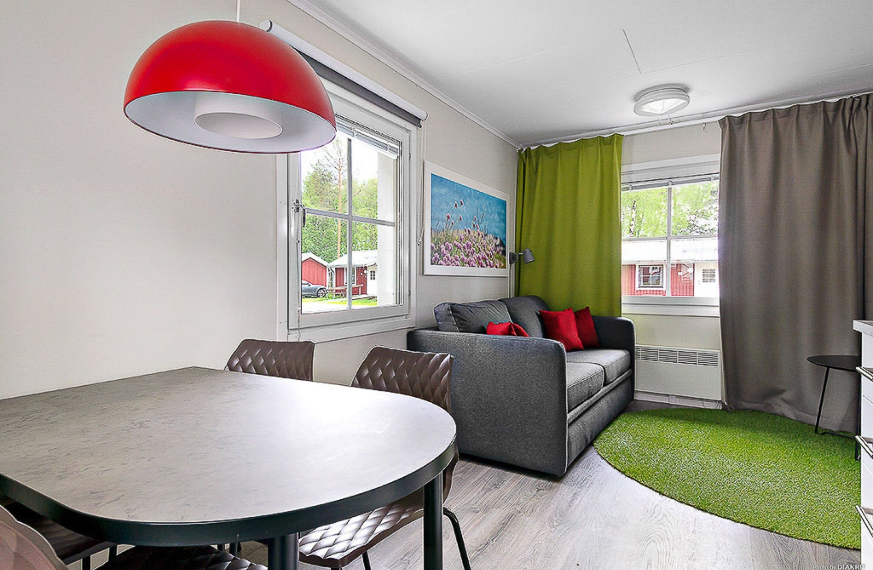 A modern living room with a dining table, sofa, and a painting on the wall.