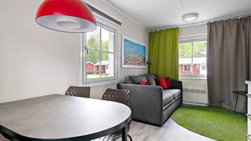 A modern living room with a dining table, sofa, and a painting on the wall.