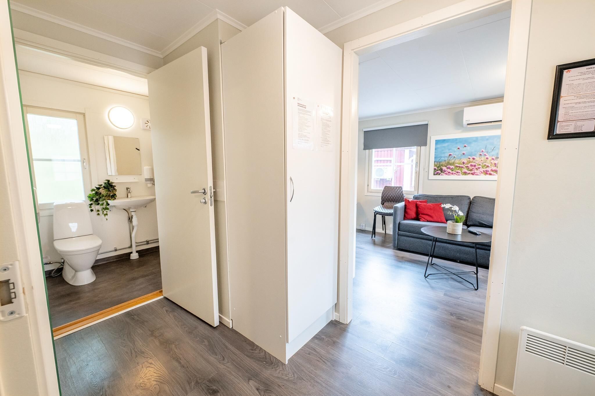A modern apartment with a visible bathroom, a living area with a sofa and a coffee table, and a door leading to another room.