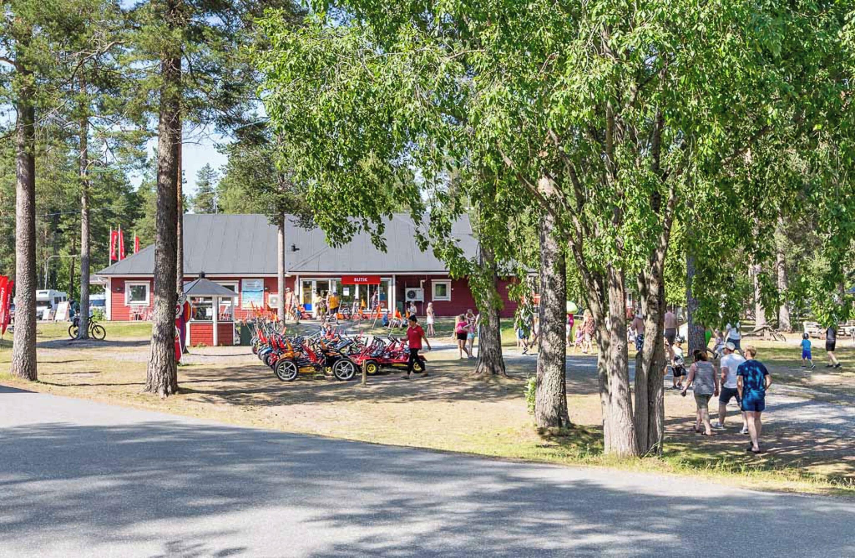 A red building with a sign that reads "BUTIK" and a row of bicycles parked in front.