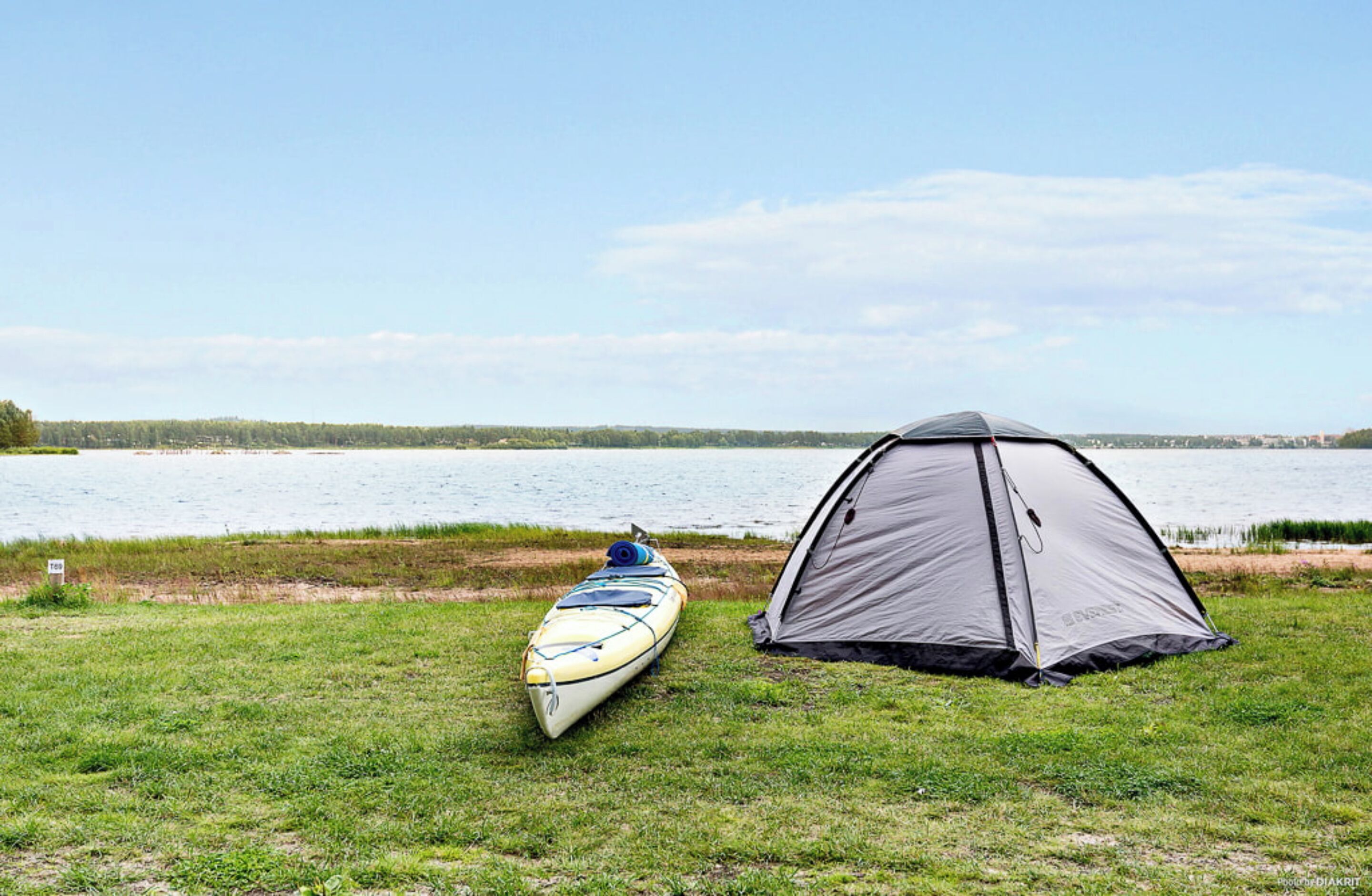 Una tienda de campaña y un kayak junto a un lago.
