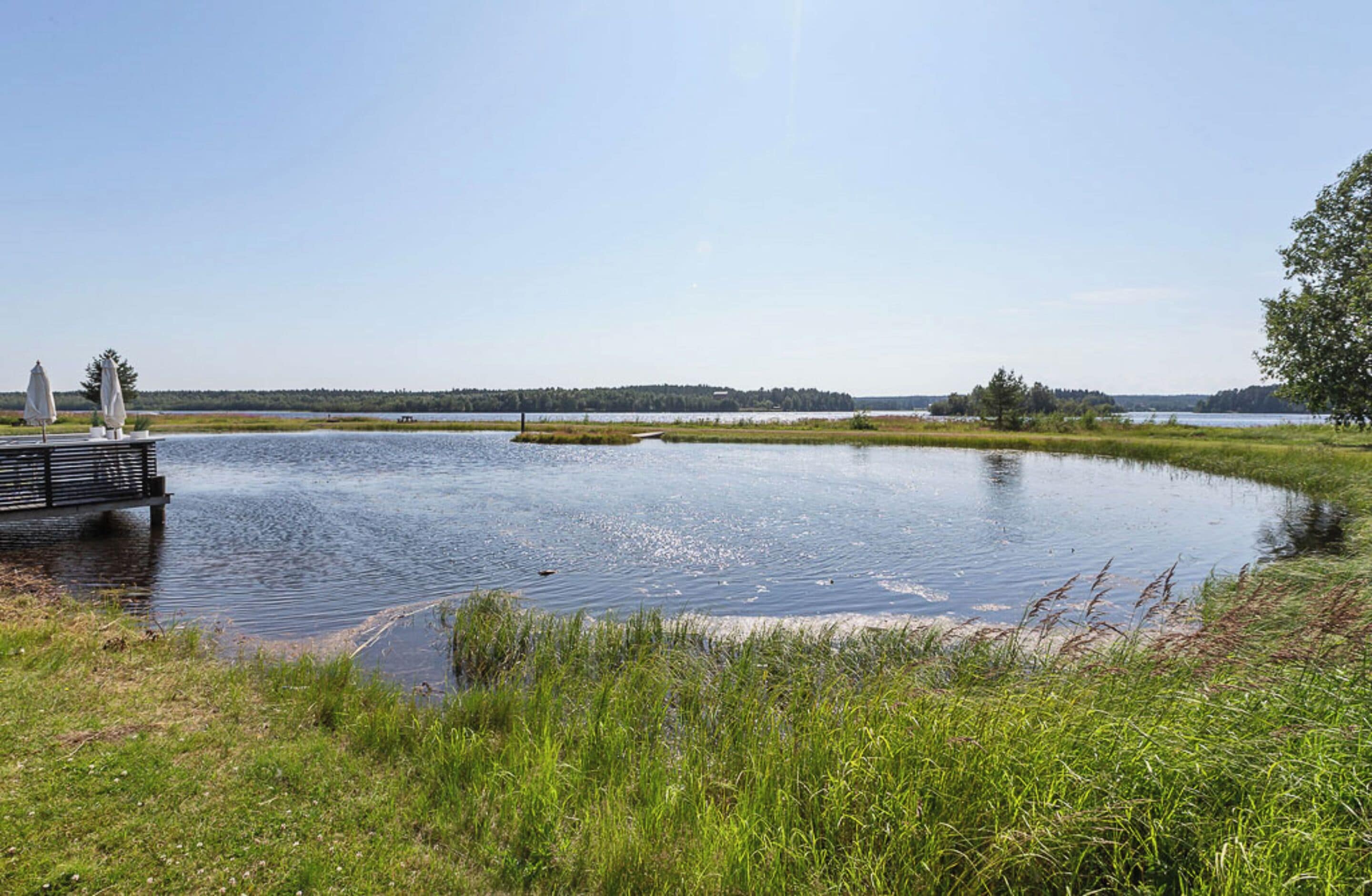 A calm lake with a dock and grassy areas.