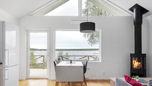 Un salon moderne doté d’une grande fenêtre, d’un coin repas et d’un poêle à bois.