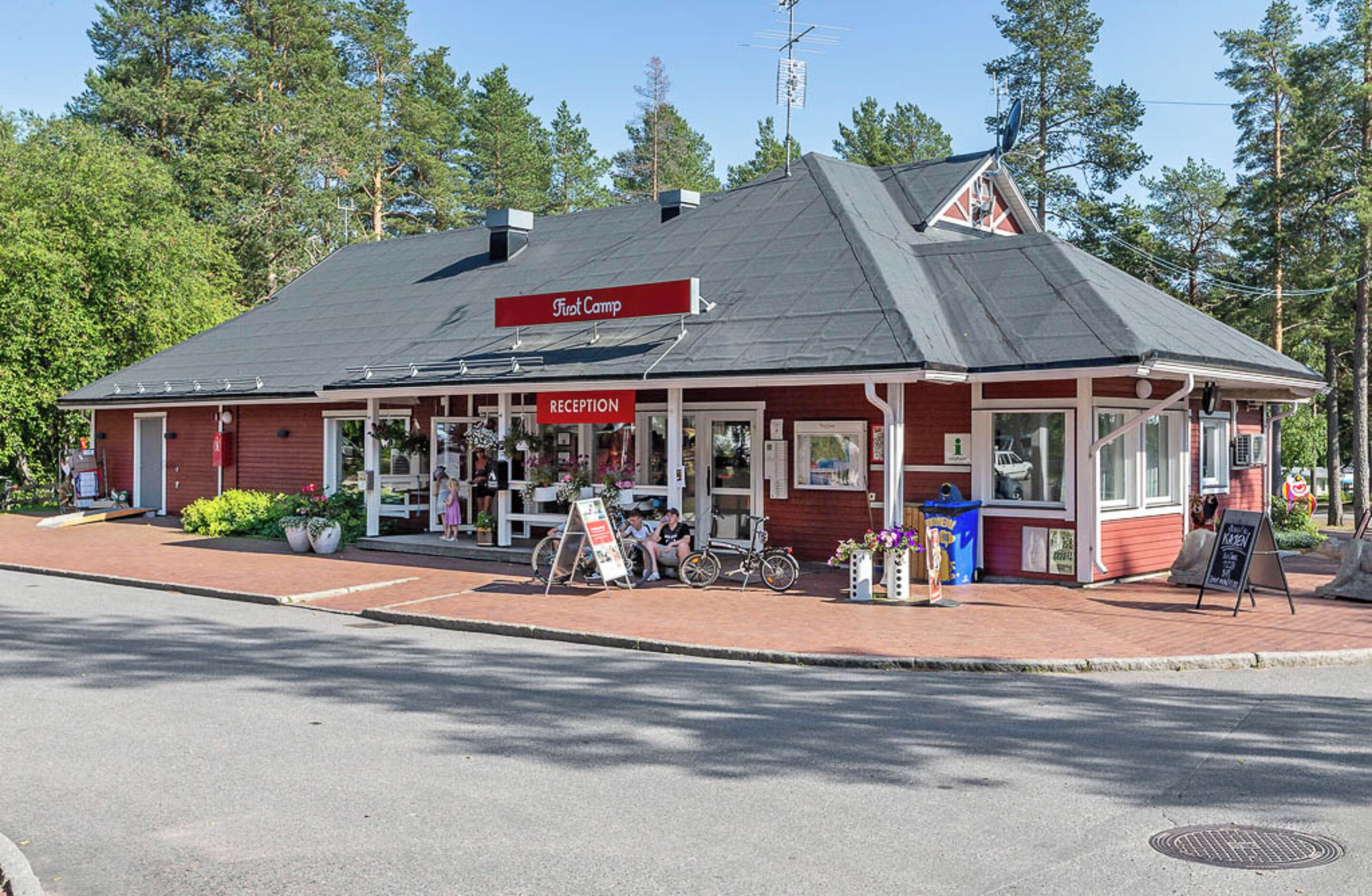 A red building with a 'Reception' sign, a bike parked outside, and a signboard.