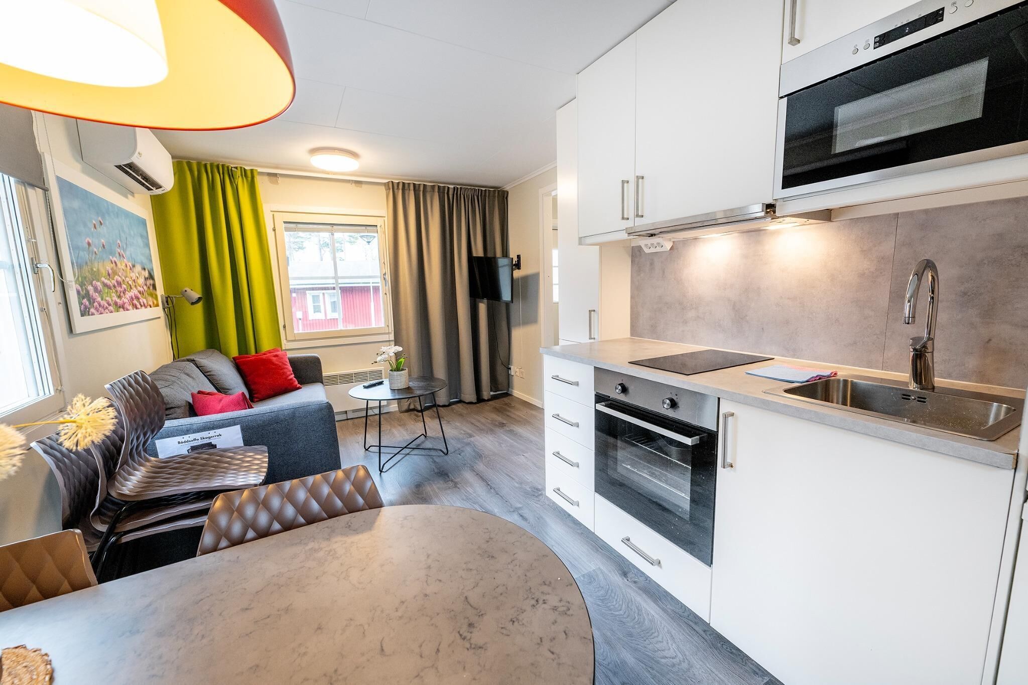 A compact kitchen with a built-in oven, a sink, and a dining area with a table and chairs.