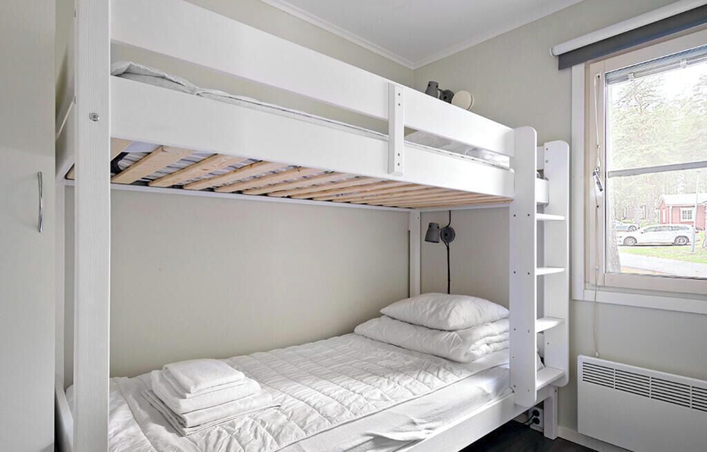 A bunk bed room with a window, a radiator, and a lamp.