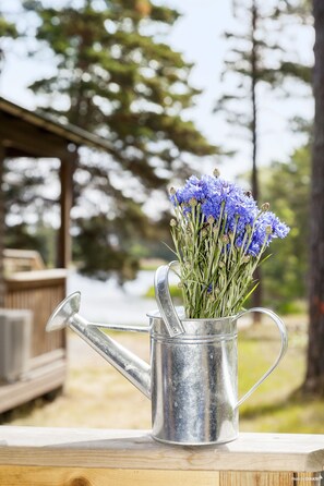 A metal watering can with a bouquet of blue flowers on a wooden surface. - First Camp Gunnarso (Oskarshamn)