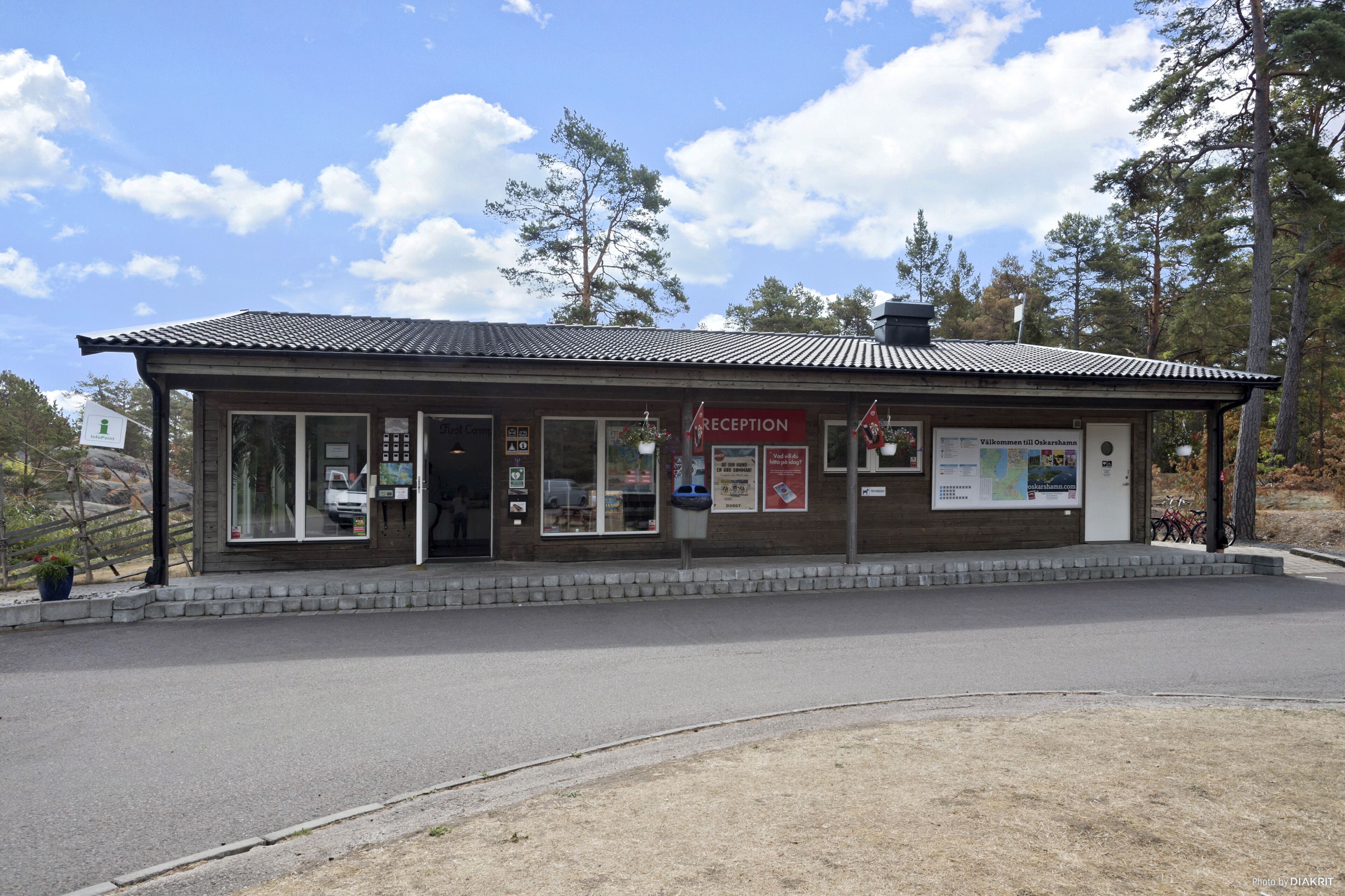 Un bâtiment d’accueil doté d’un toit en tuiles, de portes vitrées et d’affiches d’information.
