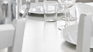 A dining table with a vase of blue flowers, a pitcher, and several wine glasses and plates.
