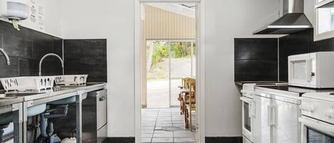 Una cocina moderna con campana de acero inoxidable, microondas y lavavajillas. Hay un ventanal que proporciona luz natural y vistas al exterior.