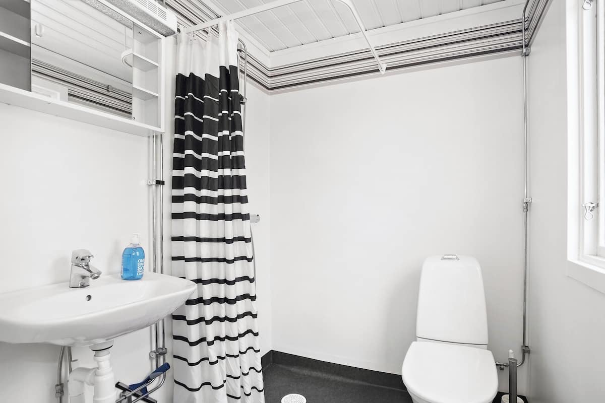 Un baño con lavamanos blanco, inodoro y cortina de ducha.