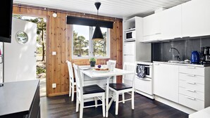 A modern kitchen with white cabinetry, a black pendant light, and a dining area with a white table and chairs.