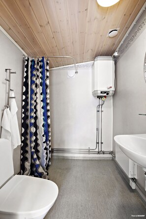 A modern bathroom with a wooden ceiling, a shower with a white tank, and a white sink. - First Camp Gunnarso (Oskarshamn)