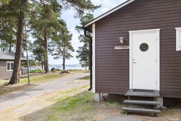 A small cabin with a white door and a nameplate reading "KANTANAK." - First Camp Gunnarso (Oskarshamn)