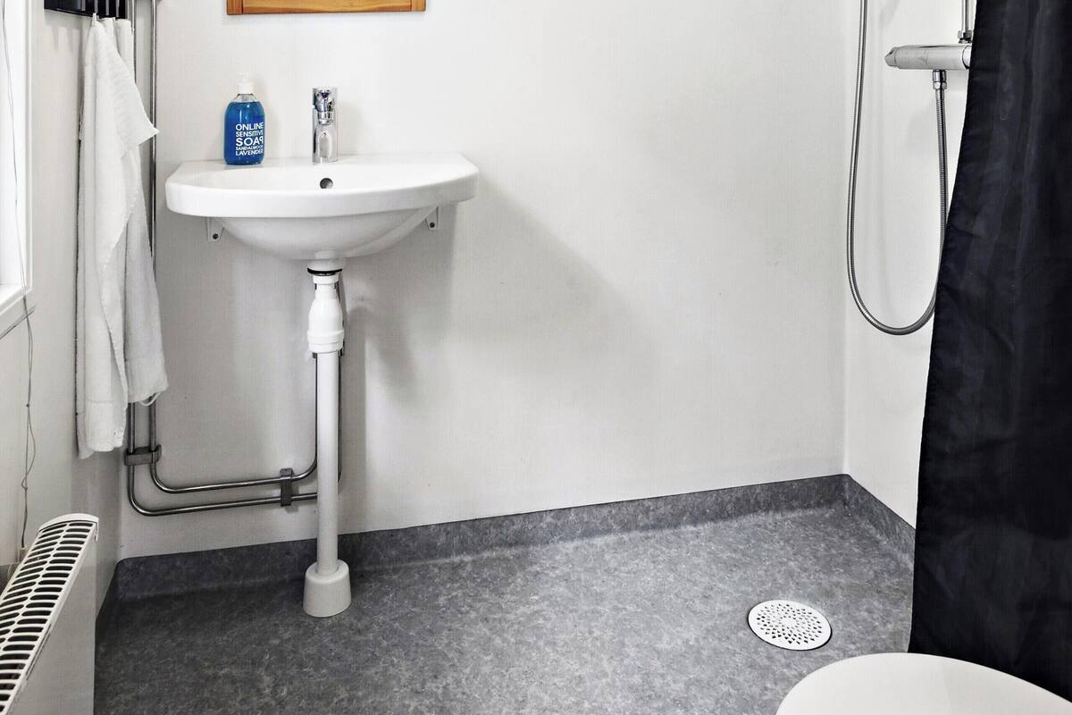 Un baño con un lavamanos blanco, un espejo, ducha e inodoro.