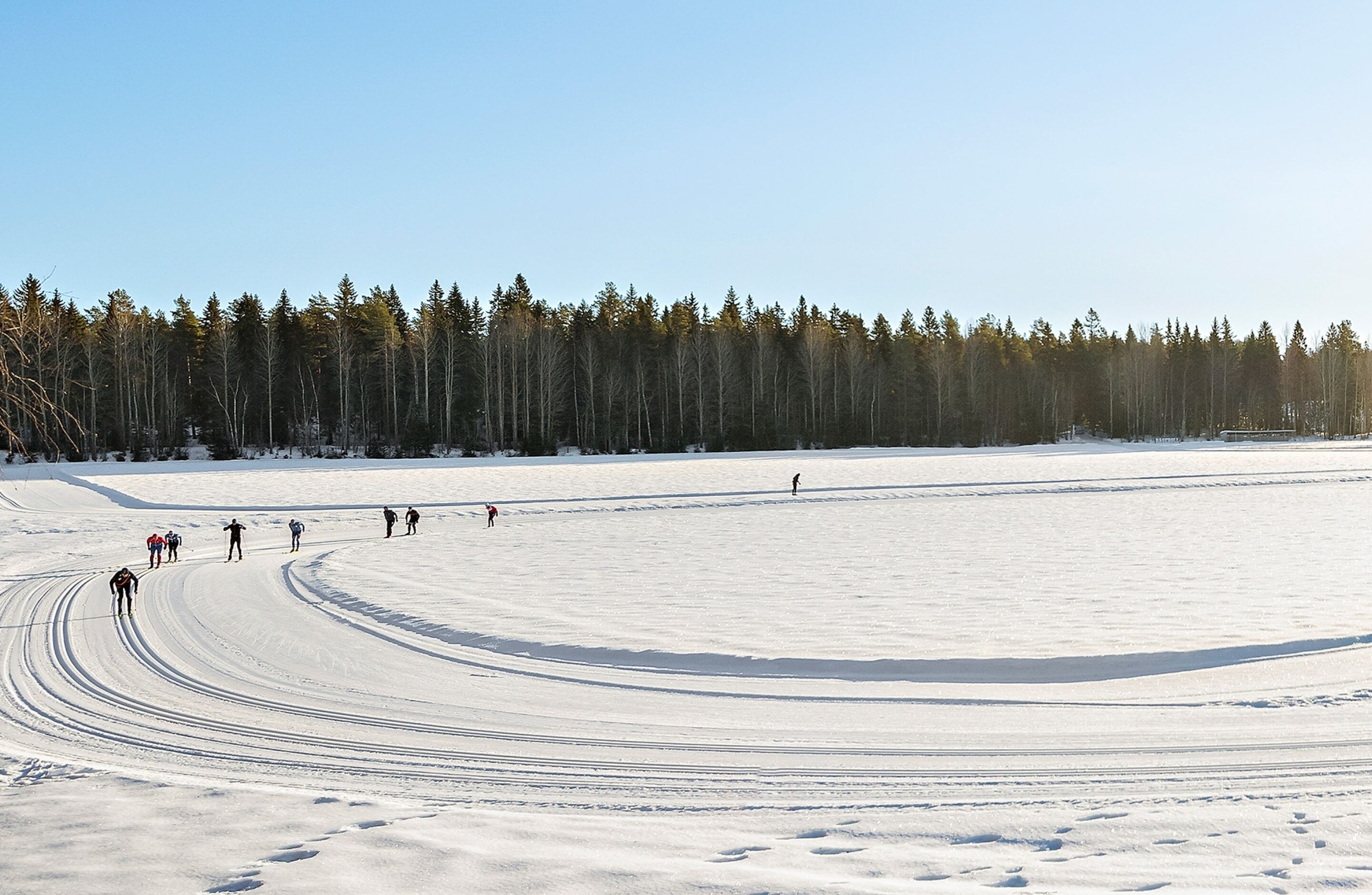 Un paysage enneigé où l’on voit un groupe de personnes en train de faire du ski.