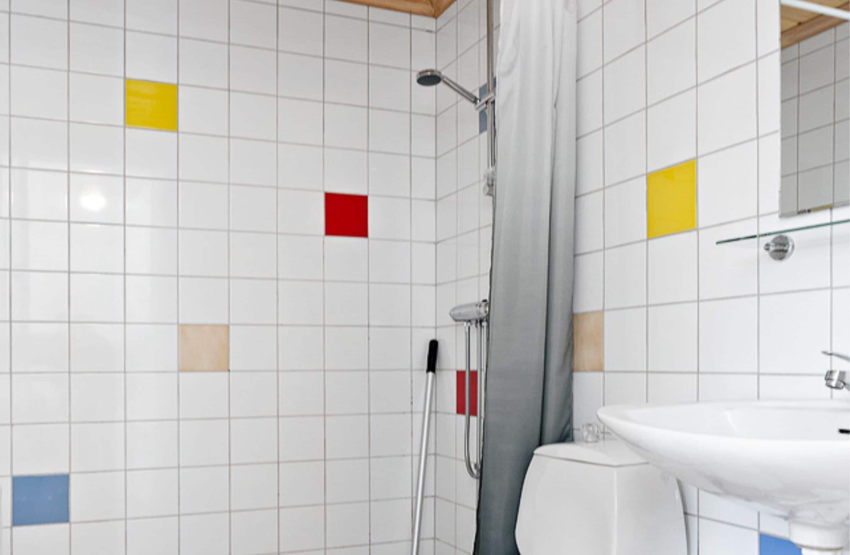 Ein Badezimmer mit weißen Fliesen, einer Dusche, einer Toilette und einem Waschbecken.