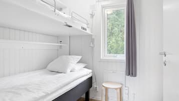 Habitación individual con una ventana, un radiador y un taburete pequeño.
