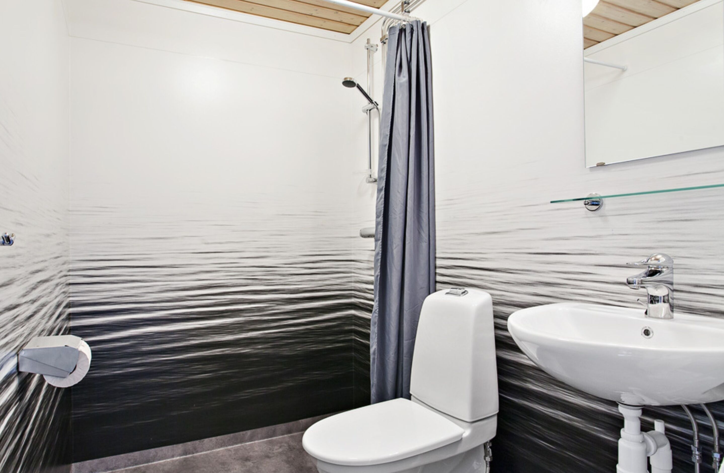 A bathroom with a white toilet, a glass shower enclosure, and a white sink.