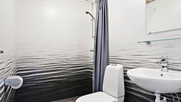A bathroom with a white toilet, a glass shower enclosure, and a white sink.