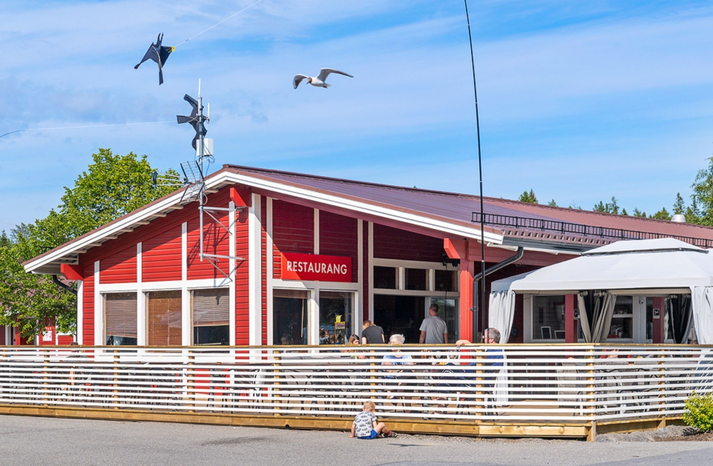 A red building with a sign reading "RESTAURANG" and a white awning.