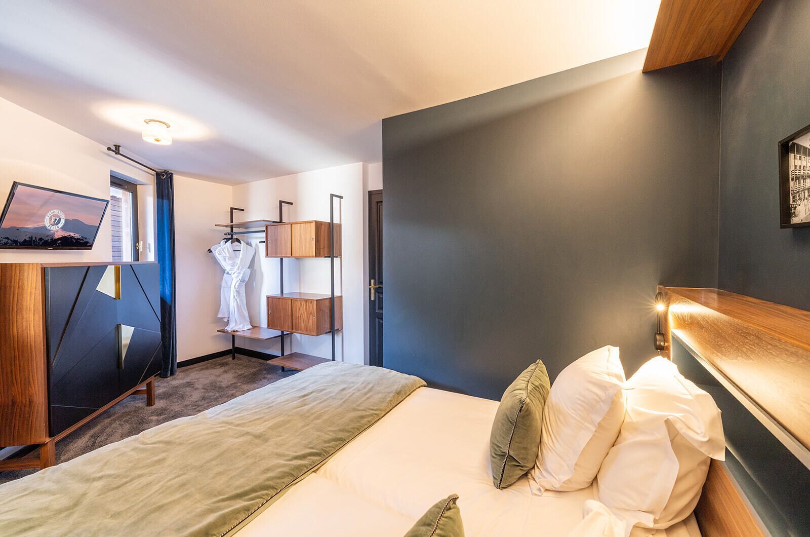 Une chambre d’hôtel avec un lit, une armoire, un miroir et un tableau au mur.