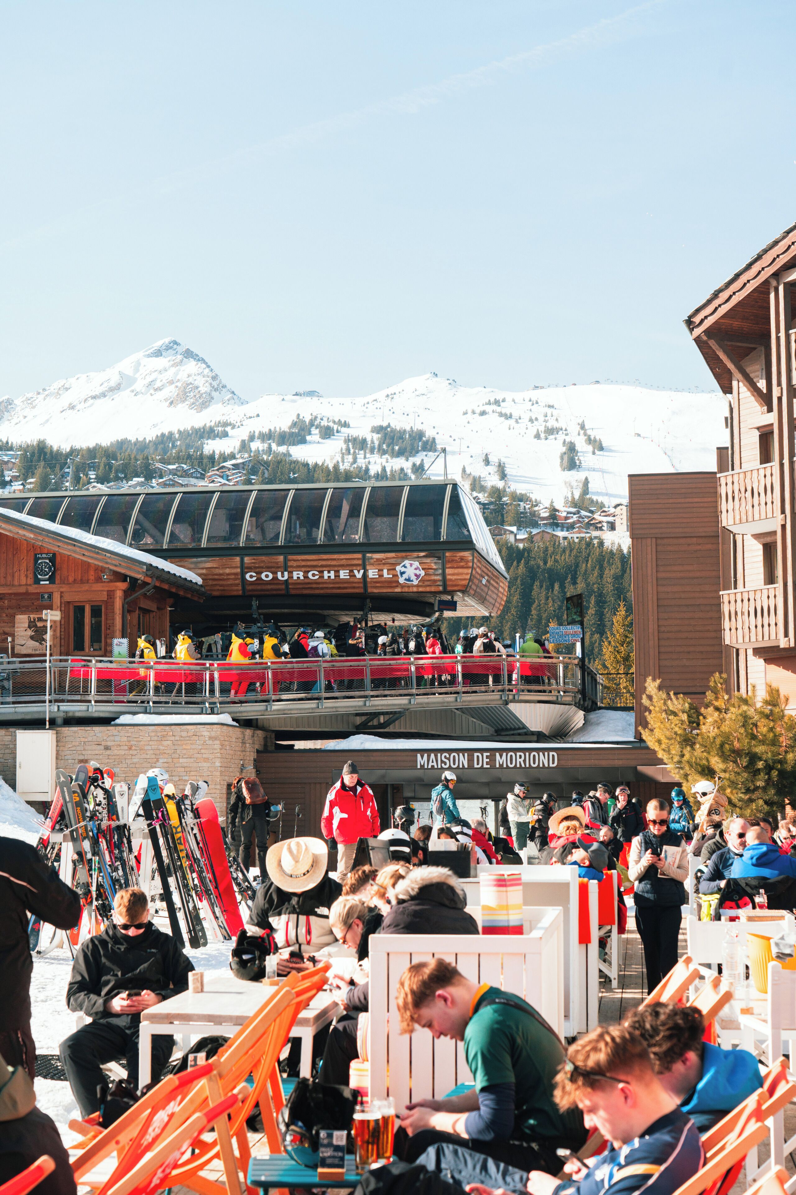 Une station de ski avec un bâtiment en bois sur lequel on peut lire les inscriptions « COURCHEVEL » et « MAISON DE MORIAND », le tout sur fond de paysage.