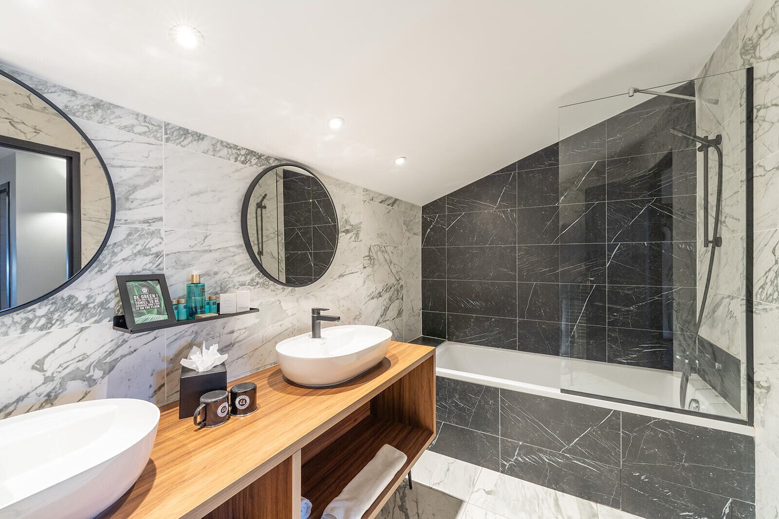 A modern bathroom with two sinks, a large mirror, and a glass-enclosed shower.