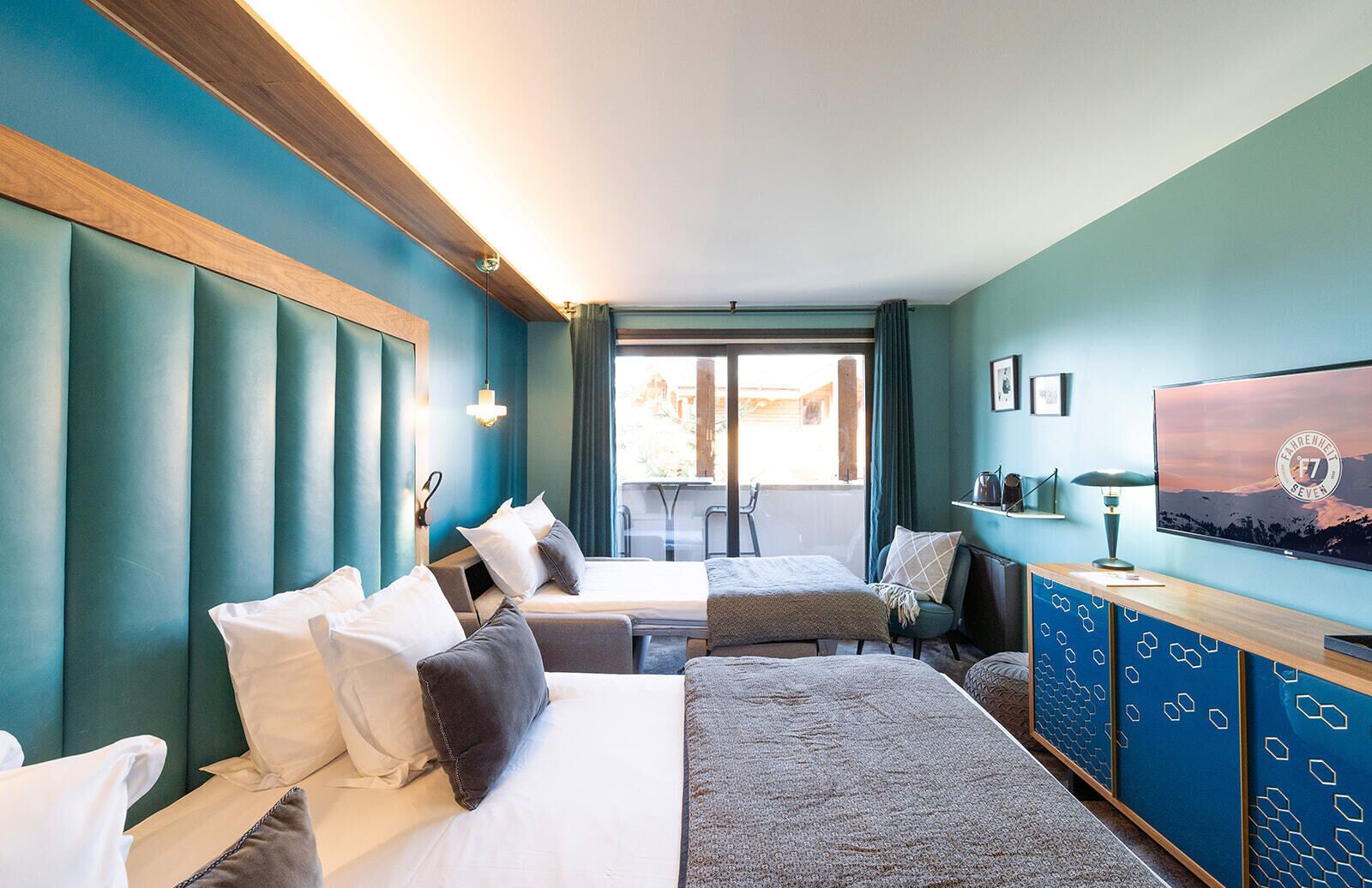 A hotel room with a large bed, a smaller bed, a desk, and a television.