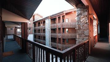 A wooden building with balconies, a stone wall, and a wooden railing.