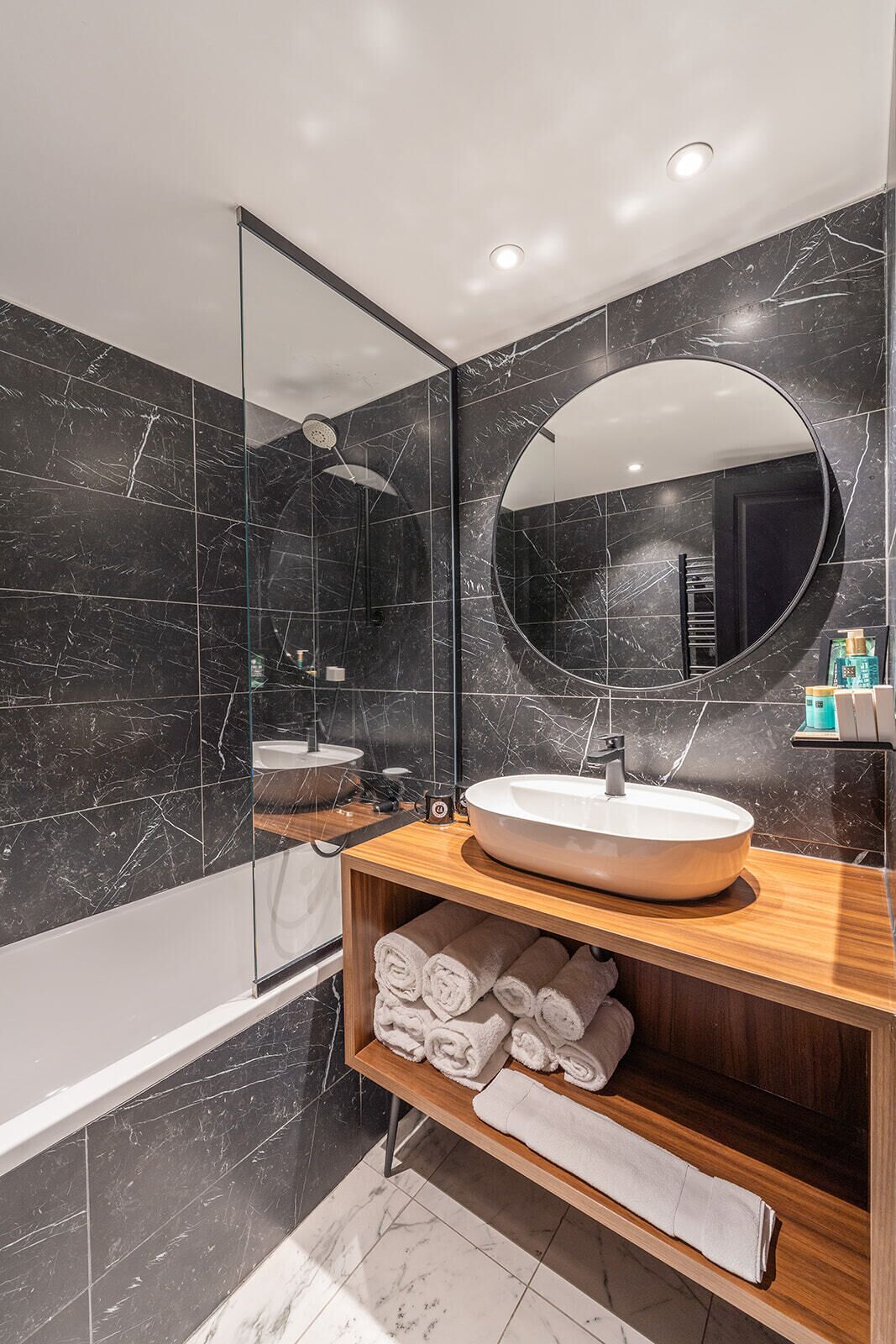 Un baño moderno con un espejo grande, un lavabo redondo y una ducha.
