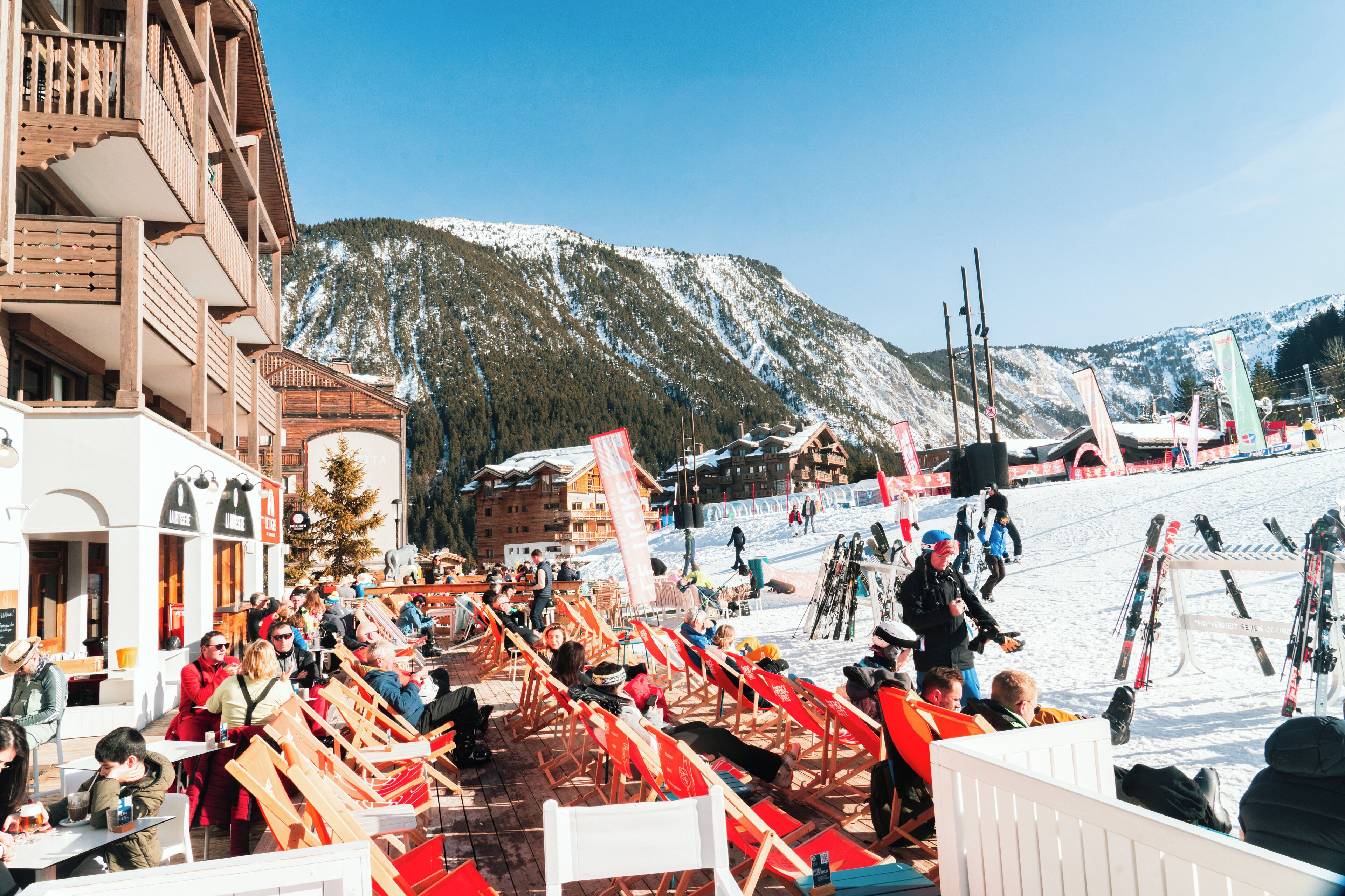 A ski resort with outdoor seating and a mountain backdrop.