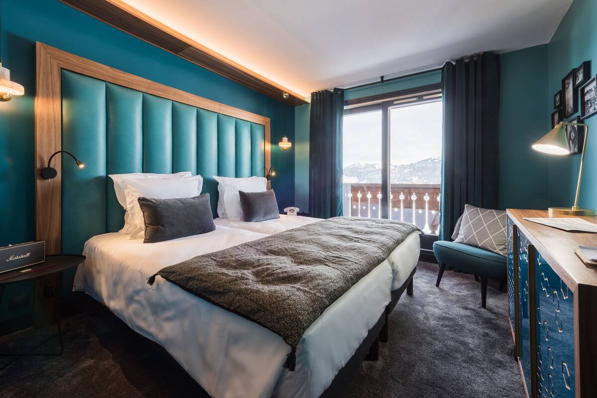 A hotel room with a large bed, a desk, and a view of the mountains.