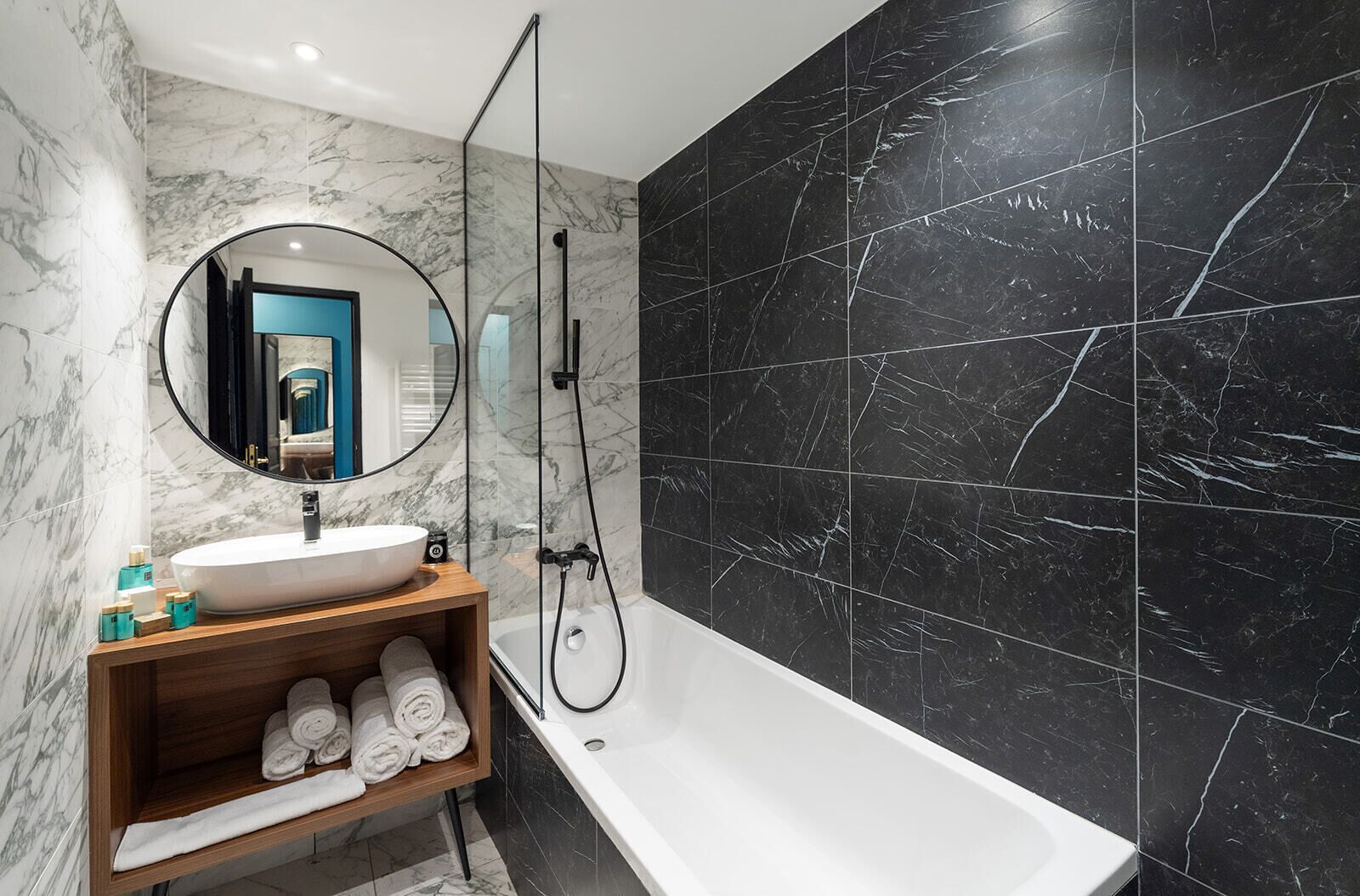 A modern bathroom with a marble vanity, a large mirror, a bathtub, and a shower.