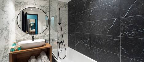 A modern bathroom with a marble vanity, a large mirror, a bathtub, and a shower.